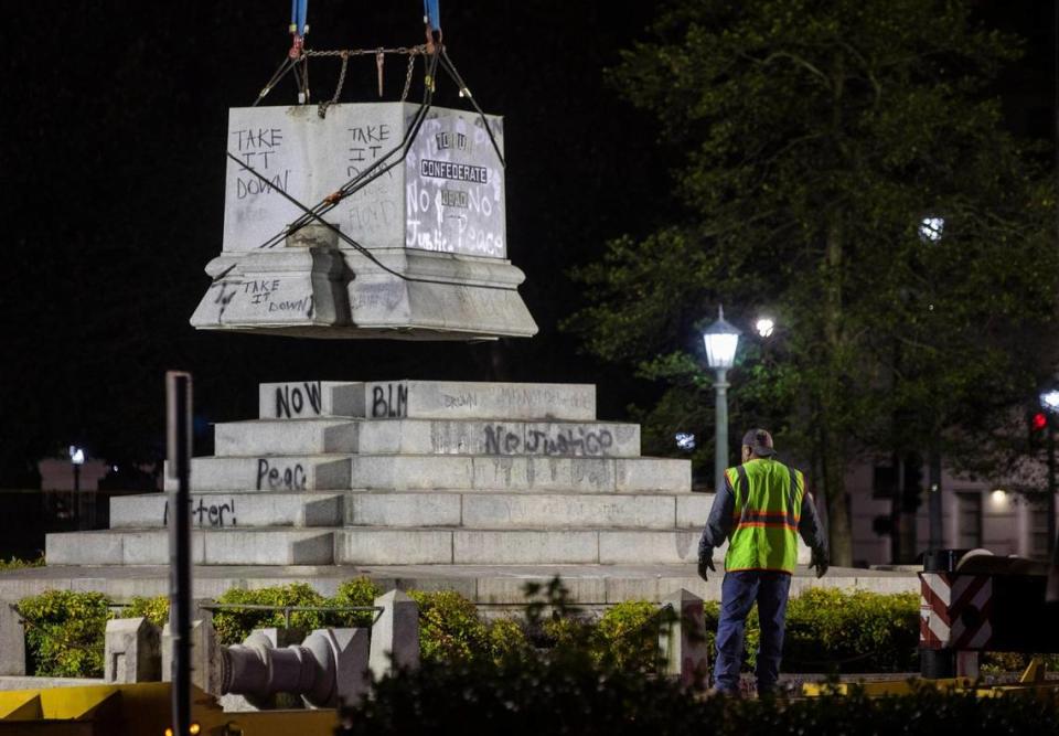 A worker watches as the final section of the 75-foot Confederate monument on the North Carolina Capitol grounds is lowered onto a trailer by a crane operator in the process to complete its removal after it stood for 125 years honoring the “bravery of the Southern soldier” in the Civil War, on Wednesday night, Jun. 23, 2020, in Raleigh, N.C. Gov. Roy Cooper ordered its removal, along with two other Confederate monuments, the day after protesters pulled down two bronze soldiers that stood midway on the monumentÕs base and law enforcement officers were injured.