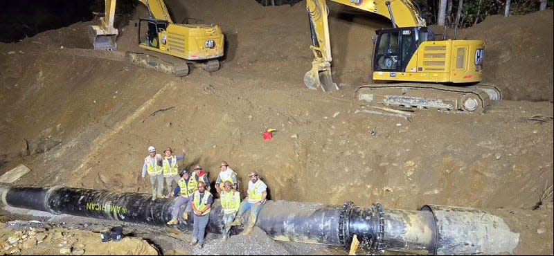 Workers pose with the newly connected North Fork reservoir water line Oct. 10, 2024, after it suffered major damage from Tropical Storm Helene.