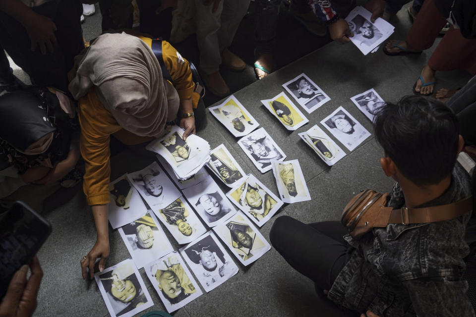 People looking for their family members inspect photographs of soccer riot victims provided by volunteers to help them identify their relatives in Malang, East Java, Indonesia, Sunday, Oct. 2, 2022. Panic at an Indonesian soccer match Saturday left over 150 people dead, most of whom were trampled to death after police fired tear gas to dispel the riots. (AP Photo/Dicky Bisinglasi)