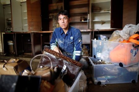 51-year-old Kairyu Takahashi, an Okayams prefectural assemblyman, tries to remove mud and debris from his house in a flood affected area in Mabi town in Kurashiki, Okayama Prefecture, Japan, July 12, 2018. Picture taken July 12, 2018. REUTERS/Issei Kato