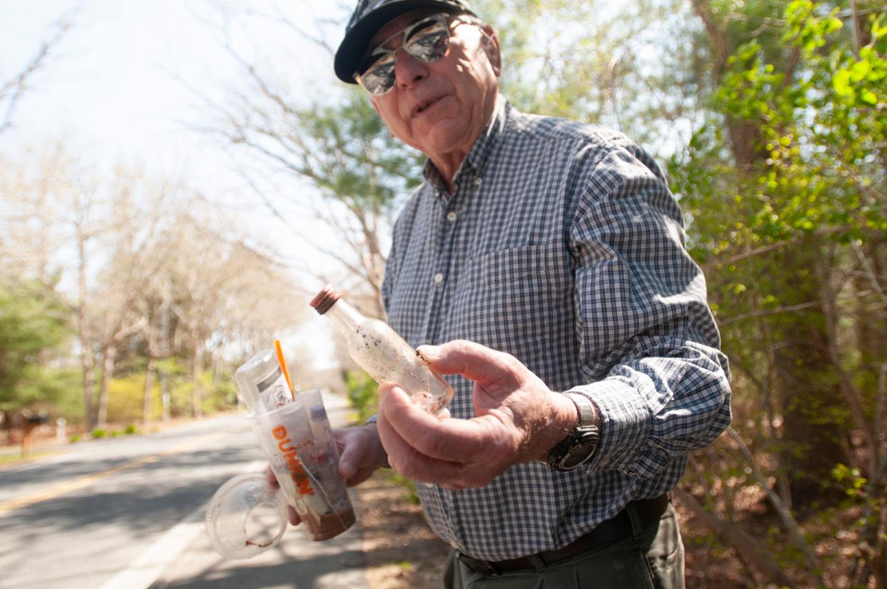 Sandwich resident Dan Tanner picks up empty nip bottles Monday along Mill Road. Tanner called the nip he holds in the photo a "vintage" bottle because it was glass rather than plastic. He is sponsoring a town meeting article to ban the sale of nip bottles in Sandwich.