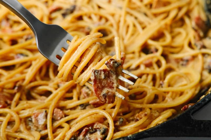 Spaghetti noodles with bacon bits and shredded cheese