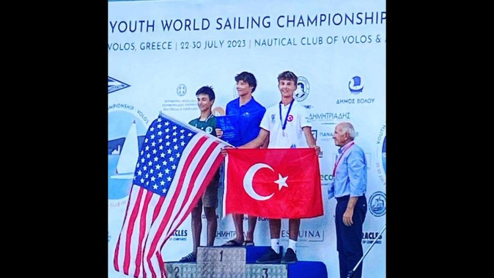 James Pine, center and holding the U.S. flag, finished first in the International Laser Class Association 4 Youth World Championship in Volos, Greece.