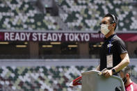 FILE - In this May 9, 2021, file photo, an official wearing a face mask waits to use a starter pistol for a women's 100 meter heat at an athletics test event for the Tokyo 2020 Olympics Games at National Stadium in Tokyo. The Tokyo Olympics are not looking like much fun: Not for athletes. Not for fans. And not for the Japanese public, who are caught between concerns about the coronavirus at a time when few are vaccinated on one side and politicians and the International Olympic Committee who are pressing ahead on the other. (AP Photo/Shuji Kajiyama, File)
