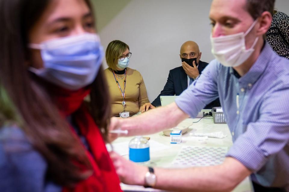 Health Secretary Sajid Javid helps fill in patient data for Amie Stott, who is receiving her booster vaccine, during a visit to Abbey vaccine centre in central London (Aaron Chown/PA) (PA Wire)
