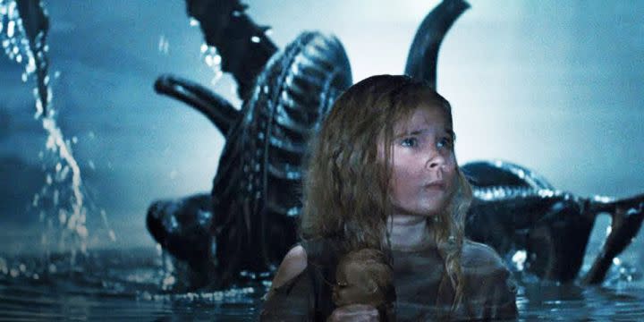 An alien rises behind Newt in Aliens