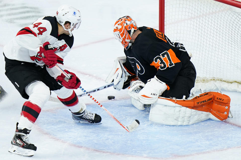 Philadelphia Flyers' Brian Elliott, right, blocks a shot by New Jersey Devils' Miles Wood during the third period of an NHL hockey game, Saturday, May 1, 2021, in Philadelphia. (AP Photo/Matt Slocum)