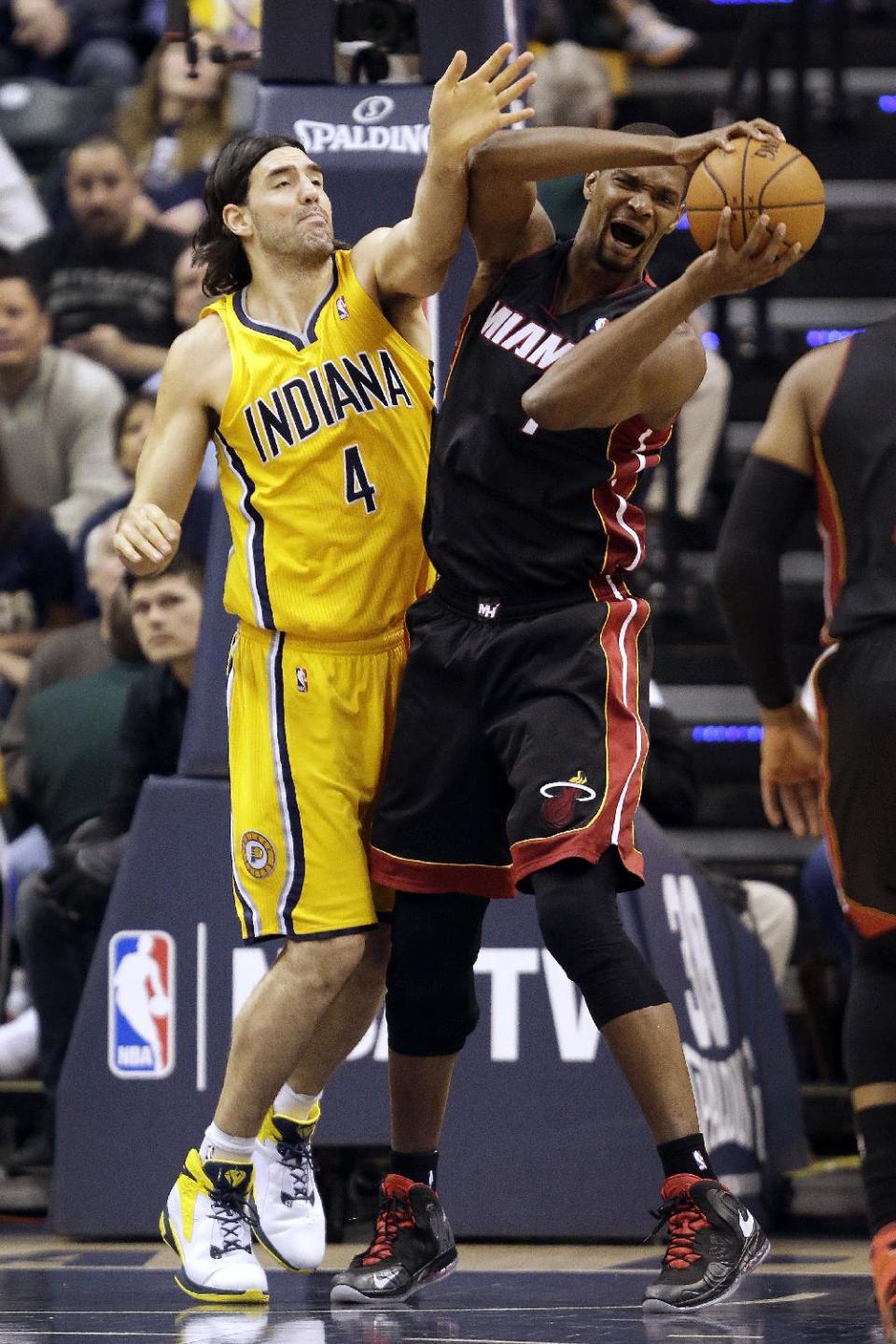 Miami Heat center Chris Bosh, right, pulls in a rebound in front of Indiana Pacers forward Luis Scola, of Argentina, during the first half of an NBA basketball game in Indianapolis, Wednesday, March 26, 2014. (AP Photo/AJ Mast)