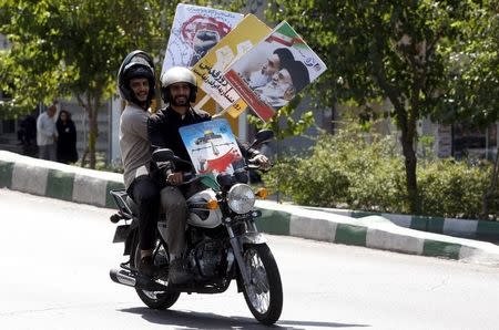 A motorcyclist carries a poster depicting Iran's Supreme Leader Ayatollah Ali Khamenei and Iran's late leader Ayatollah Khomeini during a rally marking al-Quds (Jerusalem) Day in Tehran July 10, 2015. REUTERS/Stringer/TIMA