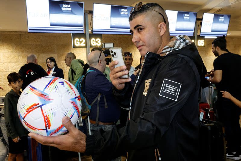 A football fan takes a photograph of a football, before boarding the first direct commercial flight between Israel and Qatar for the upcoming 2022 FIFA World Cup Qatar, at Ben Gurion International Airport, near Tel Aviv