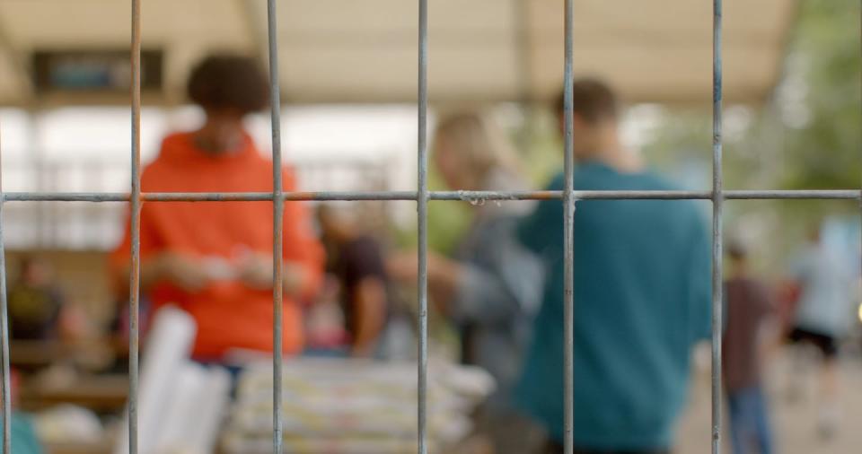 People stand together behind a window with metal bars