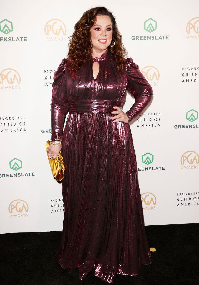 Melissa McCarthy brilló con un diseño de lamé plisado de mangas largas en color borravino que complementó con un clutch amarillo