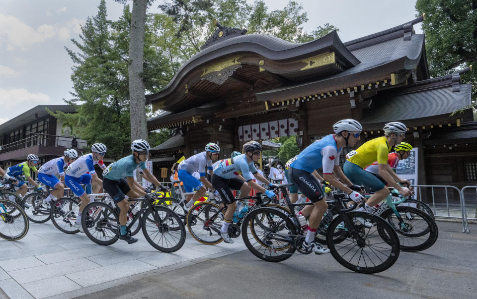 Canada's Michael Woods, foreground right, and other riders round a corner in front of the Okunitama Shrine during the men's cycling road race at the Tokyo Olympics in Tokyo on Saturday, July 24, 2021. (Frank Gunn/The Canadian Press via AP)