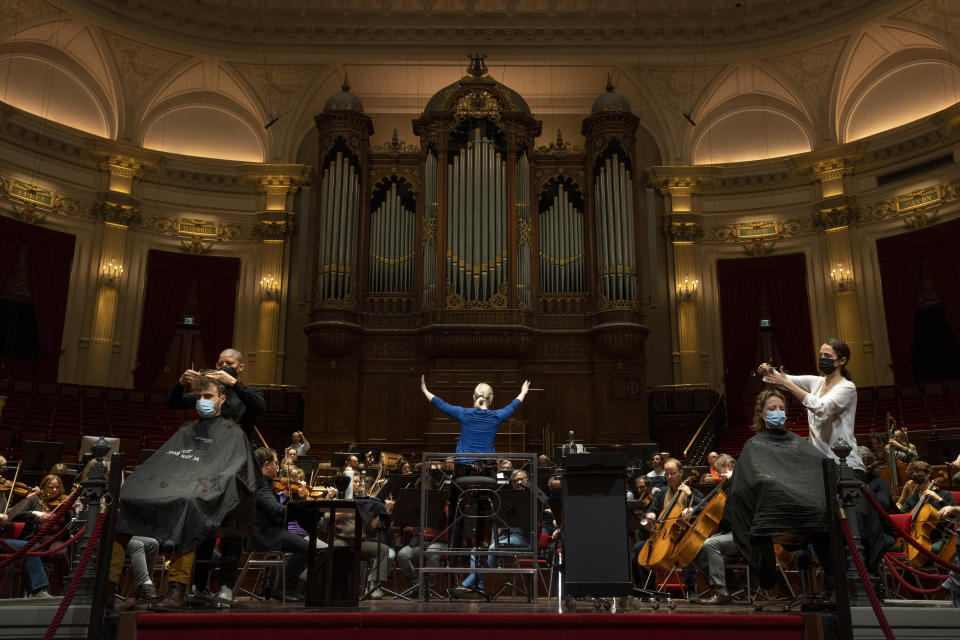 People get a haircut during a rehearsal at the Concertgebouw in Amsterdam, Wednesday, Jan. 19, 2022, as Dutch museums, theaters and concert halls played host Wednesday to businesses that are allowed to open to customers as a protest against their own continuing lockdown closures. (AP Photo/Peter Dejong)