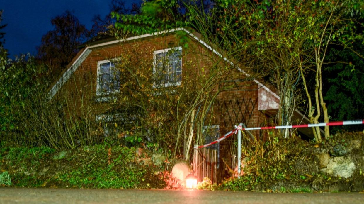 Eine Grableuchte steht neben einer Polizeiabsperrung am Eingang zu einem Haus in Wittenburg. Hier ist ein 85 Jahre alter Mann mit einem Messer getötet worden. Foto: Axel Heimken