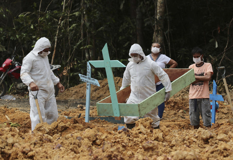 In this April 16, 2020 photo, funeral workers in protective gear prepare the grave of a woman who is suspected to have died of COVID-19 disease, at the Nossa Senhora Aparecida cemetery, in Manaus, Amazonas state, Brazil. Gravediggers buried 60 people that day, about triple the pre-virus average, according to a cemetery official. (AP Photo/Edmar Barros)