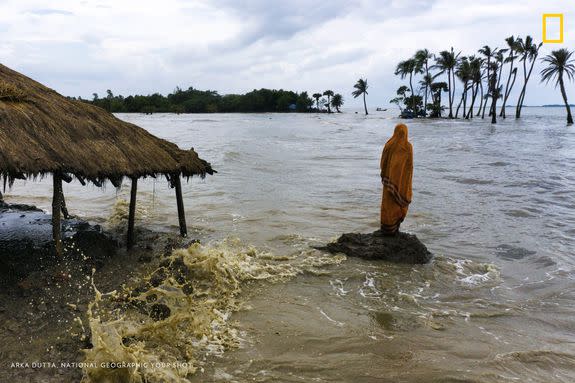 A woman stands on the Indian island of Mousuni, in the Bay of Bengal, where a rise in sea level threatens to permanently force families from their homes.