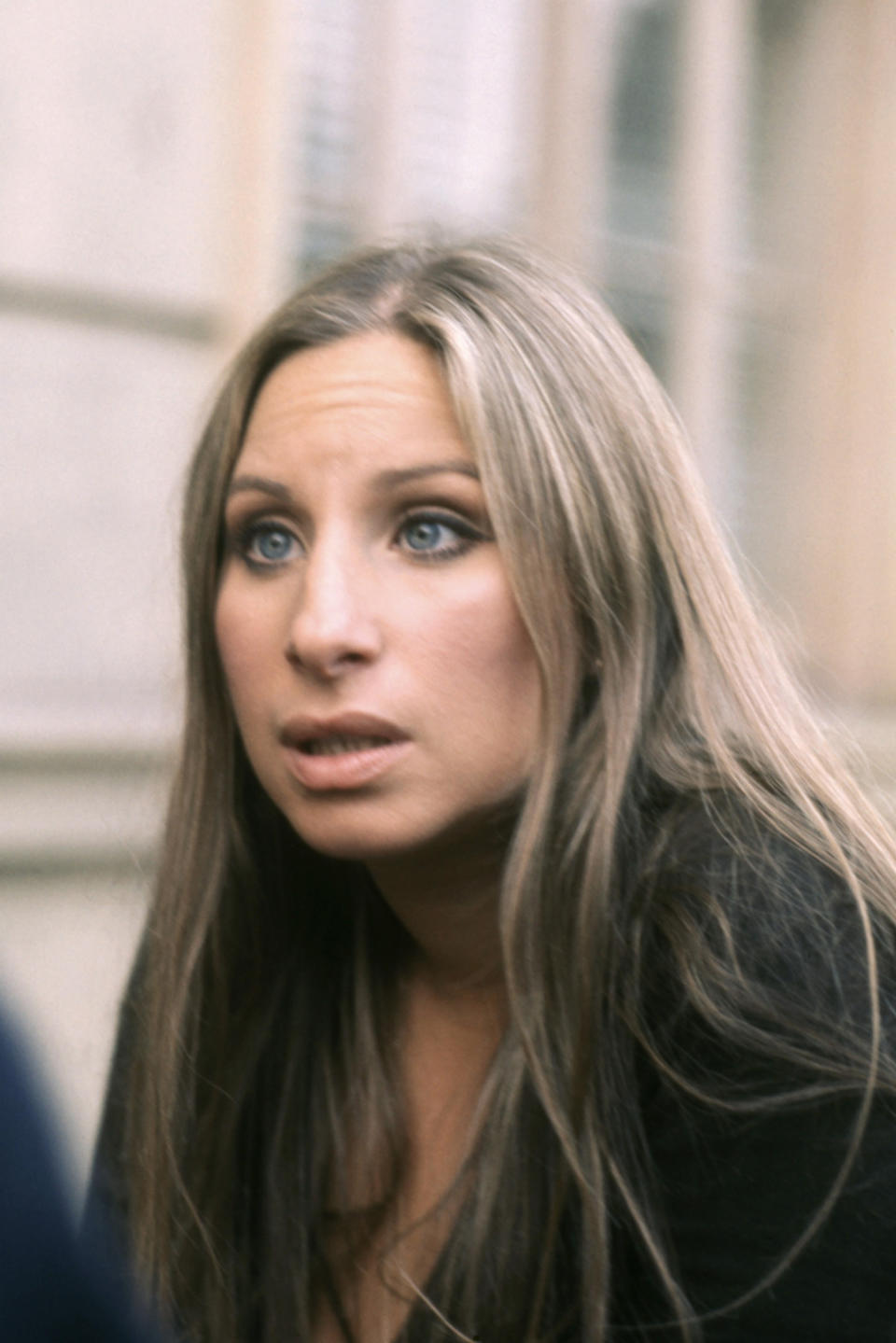 Barbra Streisand is looking up with a concerned expression, her long hair draped over her shoulders