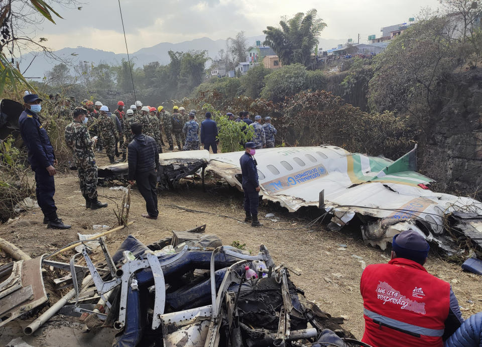 Rescatistas junto a los restos de un avión de pasajeros que se estrelló en Pokhara, Nepal, el lunes 16 de enero de 2023. El avión se estrelló al acercarse a un aeropuerto recién inaugurado en la ciudad turística de Pokhara. (AP Foto/Anish Bhattarai)