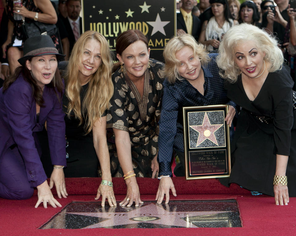 ARCHIVO - Las integrantes de la banda femenina The Go-Go's, Kathy Valentine, Charlotte Caffey, Belinda Carlisle, Gina Schock y Jane Wiedlin, de izquierda a derecha, posan junto a su estrella en el Paseo de la Fama de Hollywood en Los Angeles el 11 de agosto de 2011. La banda será incorporada al Salón de la Fama del Rock & Roll el 30 de octubre de 2021. (AP Foto/Damian Dovarganes, Archivo)