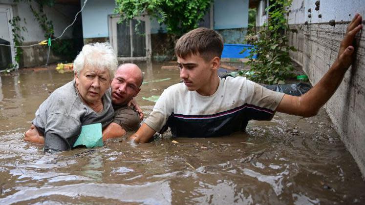 Local residents rescue an elderly man (C) from rising floodwaters in the Romanian village of Slobozia Conachi, September 14, 2024. 