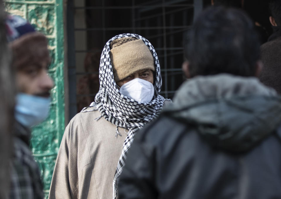 Kashmiris wait outside a polling booth to cast their votes during the first phase of District Development Councils election on the outskirts of Srinagar, Indian controlled Kashmir, Saturday, Nov. 28, 2020. Thousands of people in Indian-controlled Kashmir voted Saturday amid tight security and freezing cold temperatures in the first phase of local elections, the first since New Delhi revoked the disputed region's semiautonomous status. (AP Photo/Mukhtar Khan)