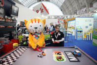 LONDON, ENGLAND - JANUARY 24: A sales representative and toy character play with radio-controlled cars on display at the 2012 London Toy Fair at Olympia Exhibition Centre on January 24, 2012 in London, England. The annual fair which is organised by the British Toy and Hobby Association, brings together toy manufacturers with retailers from around the world. (Photo by Oli Scarff/Getty Images)