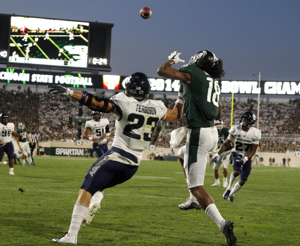 Michigan State's Felton Davis III (18) catches a pass in the end zone for a touchdown against Utah State's Gaje Ferguson (23) during the second quarter of an NCAA college football game, Friday, Aug. 31, 2018, in East Lansing, Mich. (AP Photo/Al Goldis)