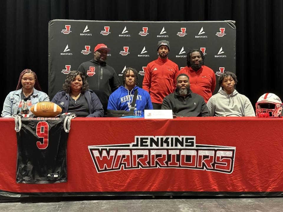 Tavion Gadson of Jenkins (center) with his family and coaches as he signed to play football at Kentucky Wednesday.