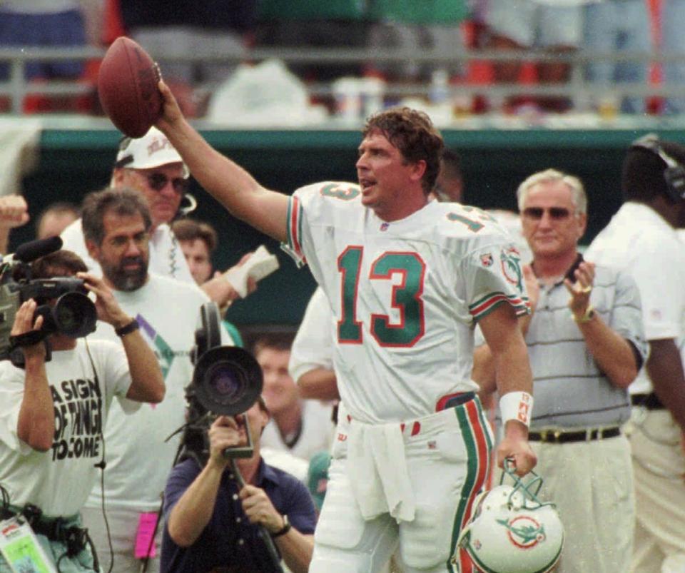Miami Dolphins quarterback Dan Marino salutes the fans in this 1995 game against the Patriots, but not for his first career reception. (AP)