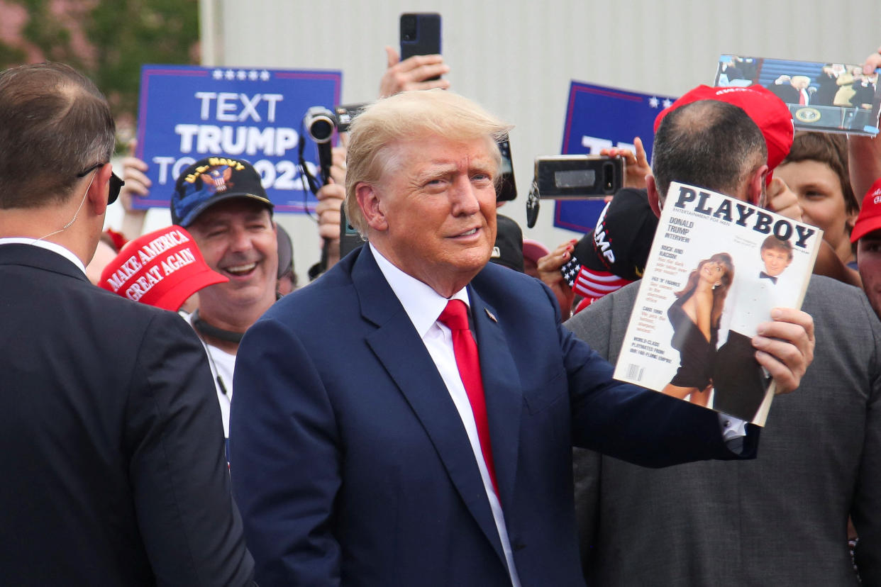 Former President Donald Trump holds up a 1990 issue of Playboy magazine with his photo on it.
