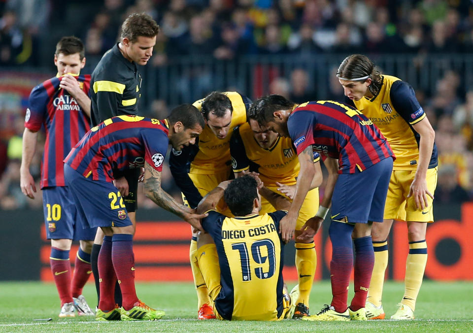 Players check on Atletico's Diego Costa, center, after he injured himself during a first leg quarterfinal Champions League soccer match between Barcelona and Atletico Madrid at the Camp Nou stadium in Barcelona, Spain, Tuesday April 1, 2014. (AP Photo/Emilio Morenatti)
