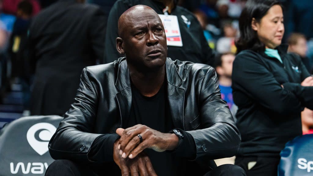 michael jordan sitting courtside at a basketball game with his his crossed and looking ahead