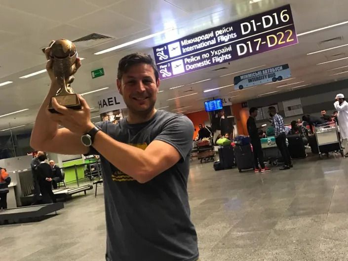 A man holding up a trophy in an airport.