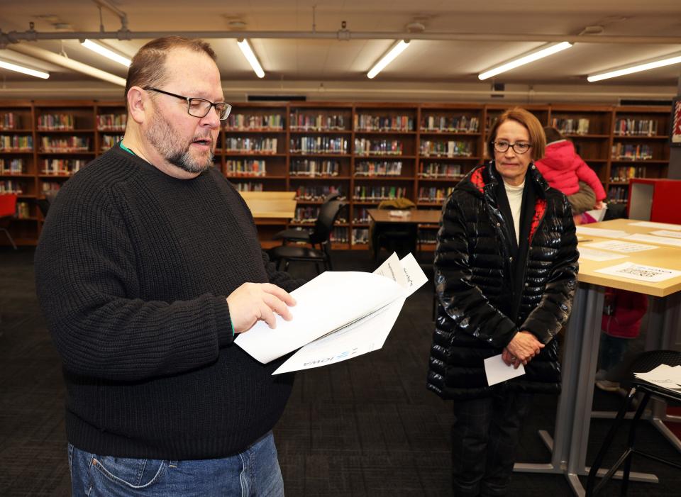 Caucus Chair Kevin Marken reads the rules and Des Moines Mayor Connie Boesen listens as Democrats brave sub-zero weather to gather in person on Iowa Caucus night in Polk County on Monday at the East High School library in Des Moines.