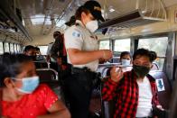 A police officer checks the documentation of the passengers to check for migrants coming from the caravan of Central Americans, to prevent them from continuing their journey to the U.S, at a checkpoint, in Pajapita