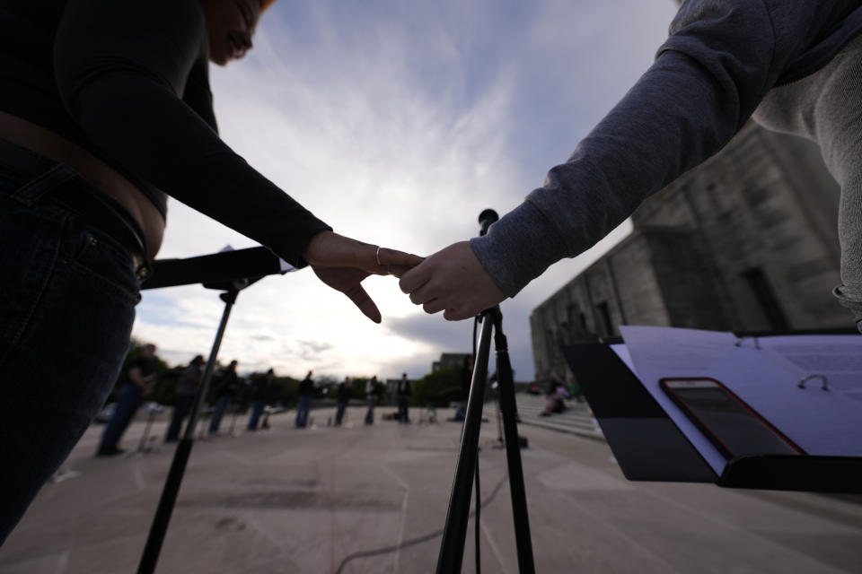 Benjamin Franklin High playwriting class students hold hands as they perform their play "The Capitol Project" on the steps of the Louisiana Capitol in Baton Rouge, La., Wednesday, March 27, 2024. (AP Photo/Gerald Herbert)