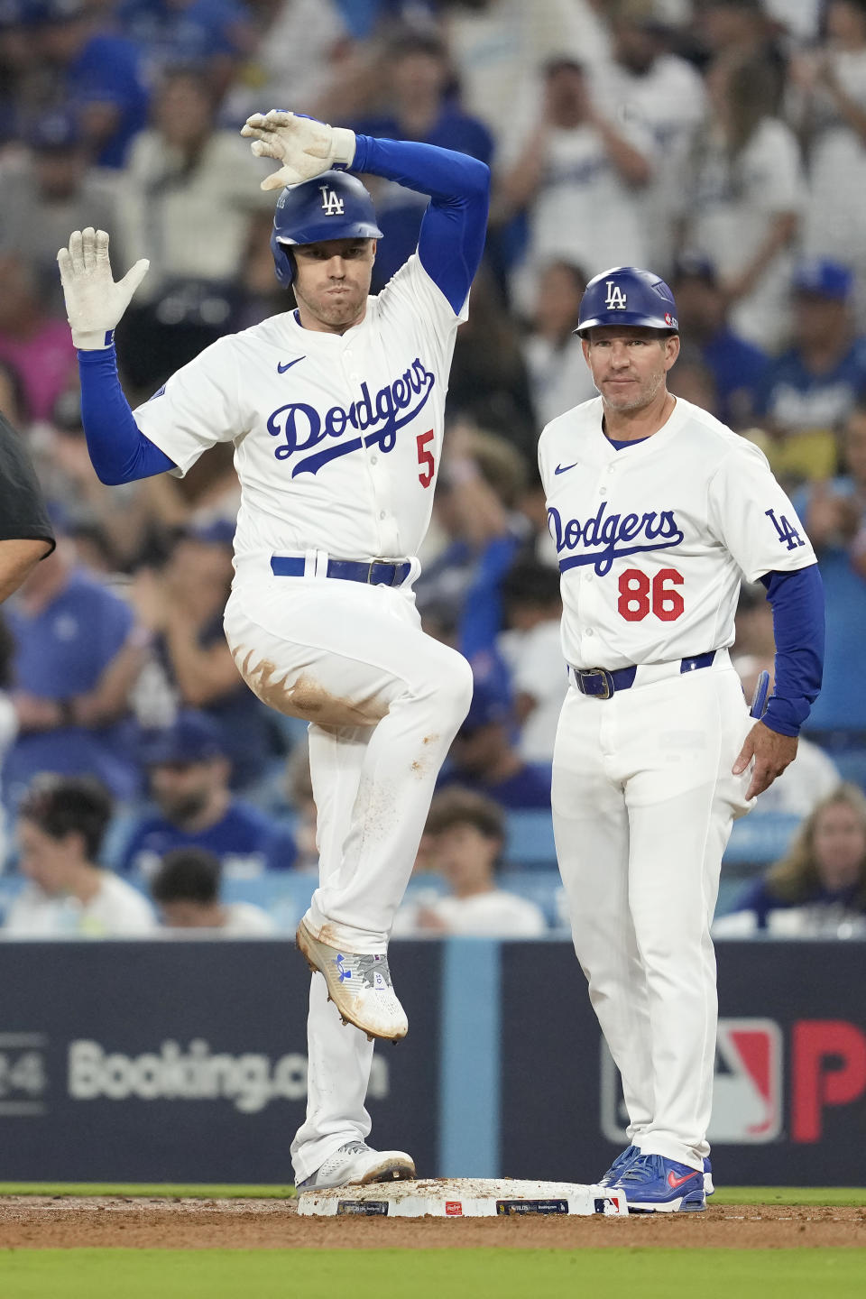 Los Angeles Dodgers' Freddie Freeman, left, celebrates after hitting a single next to first base coach Clayton McCullough (86) during the third inning in Game 1 of baseball's NL Division Series against the San Diego Padres, Saturday, Oct. 5, 2024, in Los Angeles. (AP Photo/Ashley Landis)