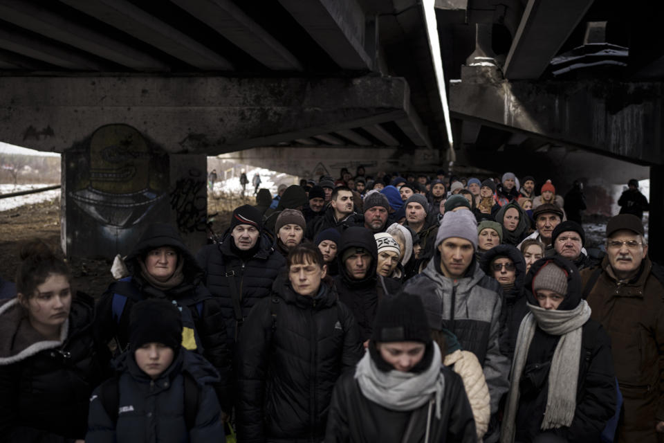 People crowd under a destroyed bridge in Irpin as they try to flee Russian shelling. (Felipe Dana/AP)