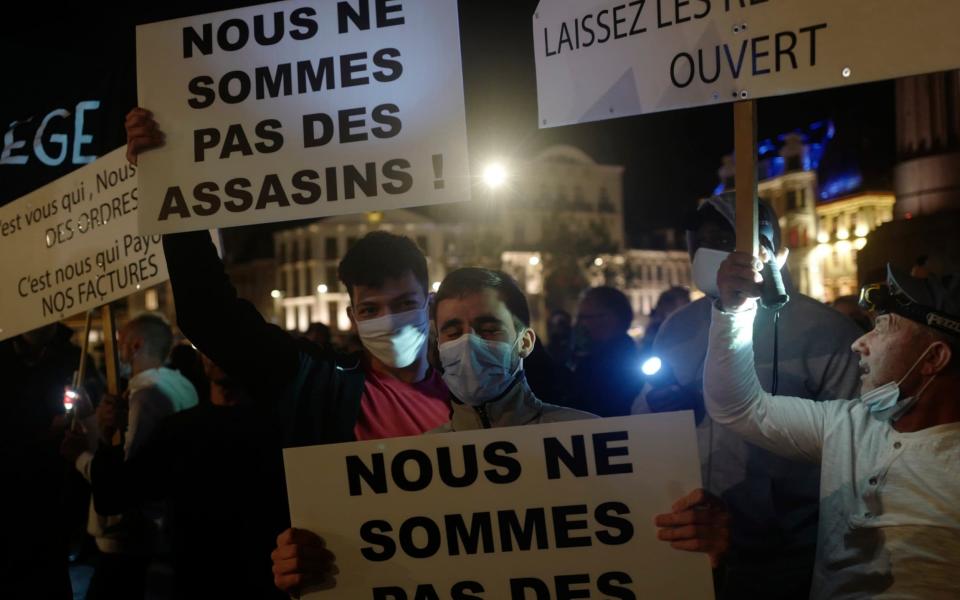 Restaurants and bar owners carry placards reading 'We are not murderers' - AP Photo/Michel Spingler