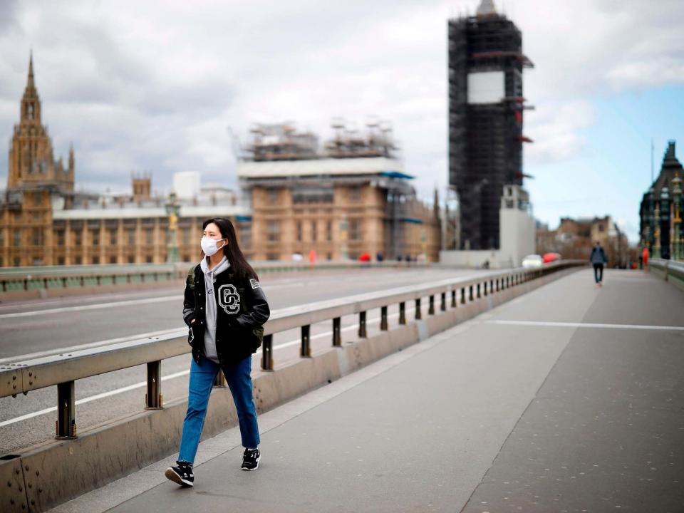 A woman wearing a face mask as a precautionary measure against Covid-19 walks across a deserted Westminster Bridge in London: Tolga Akmen/AFP/Getty