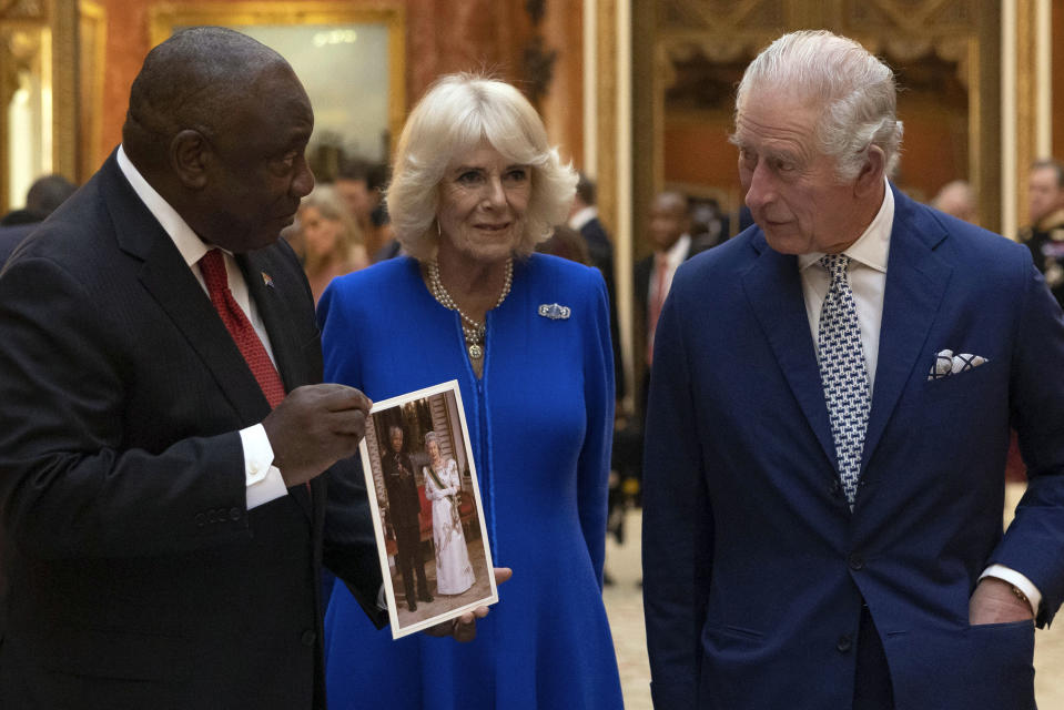 Britain's King Charles III, Camilla, the Queen Consort and President Cyril Ramaphosa of South Africa, left, view a display of South African items from the Royal Collection, including a photograph of President Nelson Mandela and Queen Elizabeth II, at Buckingham Palace, London, Tuesday Nov. 22, 2022, during the two day state visit to the UK by the South African president. (Dan Kitwood/Pool via AP)