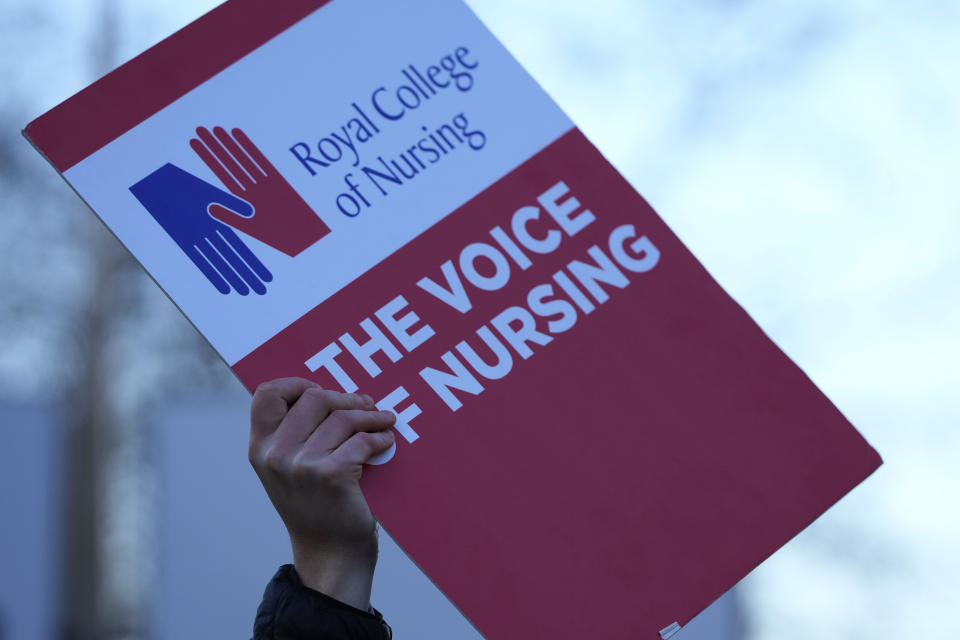 A demonstrator holds up a placard in support of the strike by nurses outside St Thoma's Hospital in London, Tuesday, Dec. 20, 2022. Nurses in England, Wales and Ireland will stage the biggest strike in the history of the Royal College of Nursing (RCN). Up to 100,000 members will walk out at 65 NHS organisations. (AP Photo/Alastair Grant)