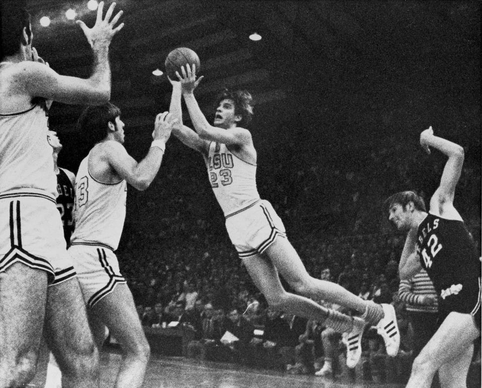 FILE - Louisiana State's Pete "Pistol" Maravich (23) flies through the air during record breaking performance against Mississippi in Baton Rouge, La., Feb. 1, 1970, to become college basketball's leading scorer of all-time. At right is University of Mississippi's Tom Butler (42) and at left are LSU's Danny Hester (35) and Bill Newton (43). Those who played with, followed or knew the late Maravich are conflicted about the seemingly inevitable moment — likely this Sunday — when he could be supplanted by Iowa women's basketball sensation Caitlin Clark atop the NCAA's all-time scoring list. (AP Photo/File)