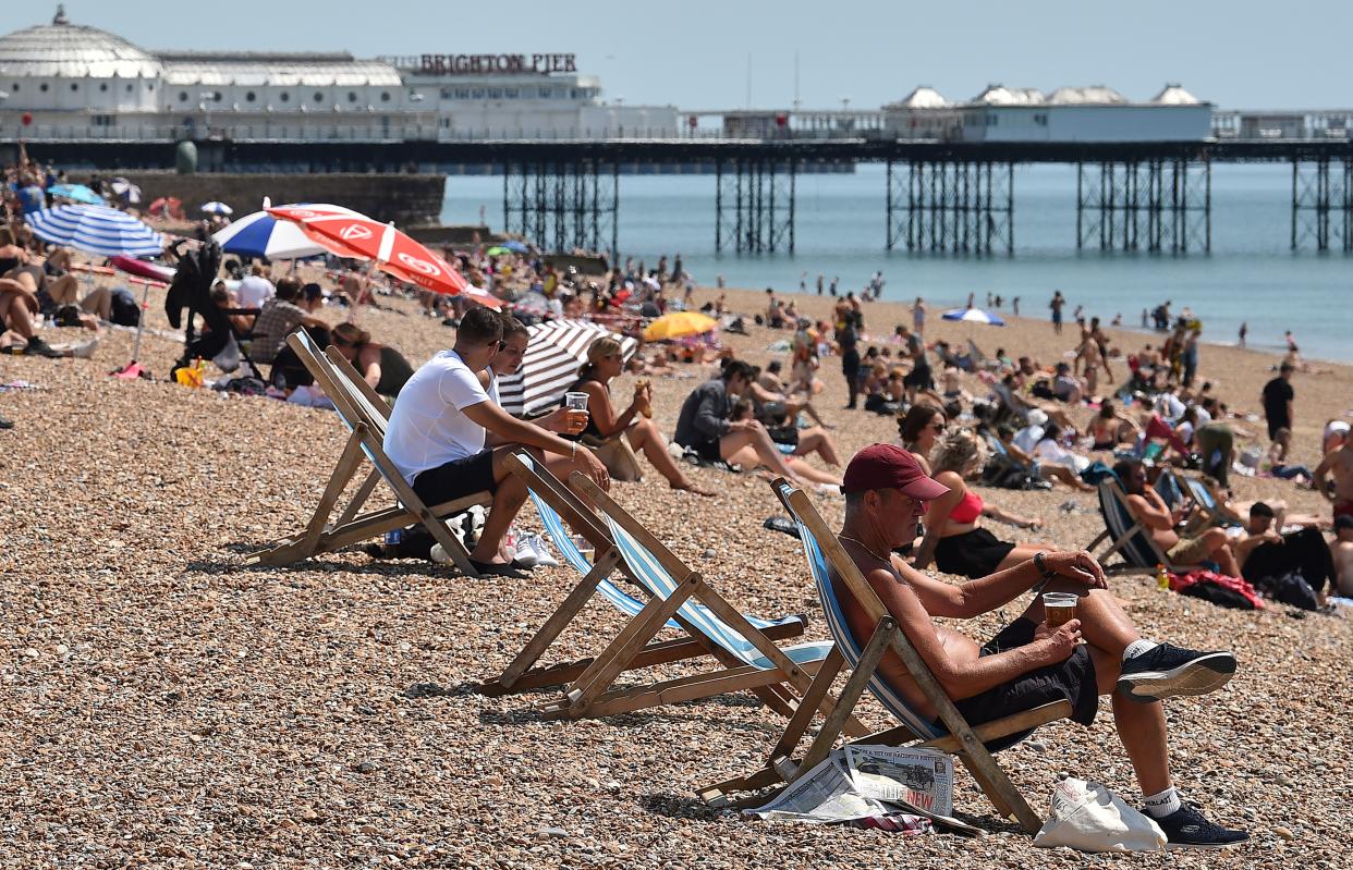 People sit in deckchairs as they enjoy the sunshine on the beach near the Brighton Pier in Brighton on the south coast of England on June 2, 2020 following a further relaxation of the novel coronavirus COVID-19 lockdown rules. - Suspected and confirmed cases of deaths from the coronavirus outbreak in Britain have risen to 48,000, according to official data published Tuesday. (Photo by Glyn KIRK / AFP) (Photo by GLYN KIRK/AFP via Getty Images)