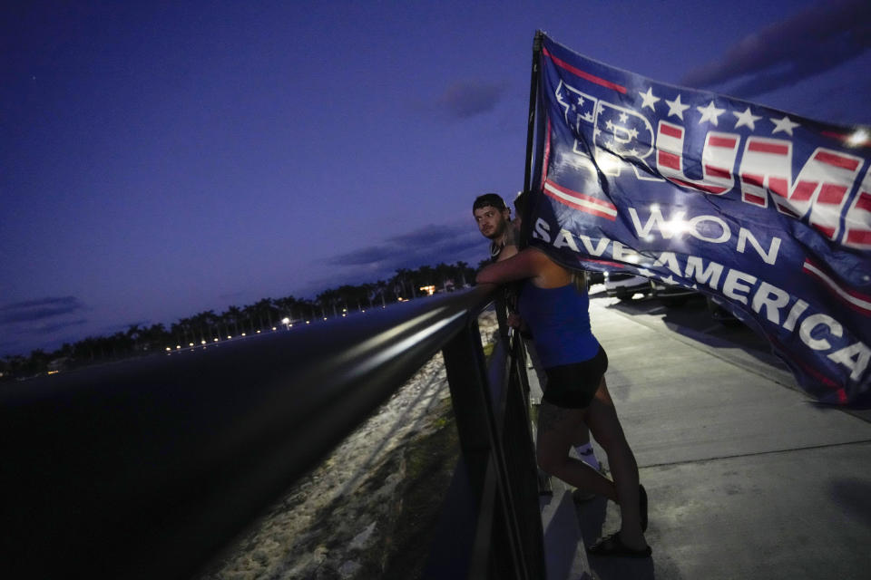 People hold a flag to show their support for former President Donald Trump following the news that Trump has been indicted by a Manhattan grand jury, Thursday, March 30, 2023, near Trump's Mar-a-Lago estate in Palm Beach, Fla. (AP Photo/Rebecca Blackwell)