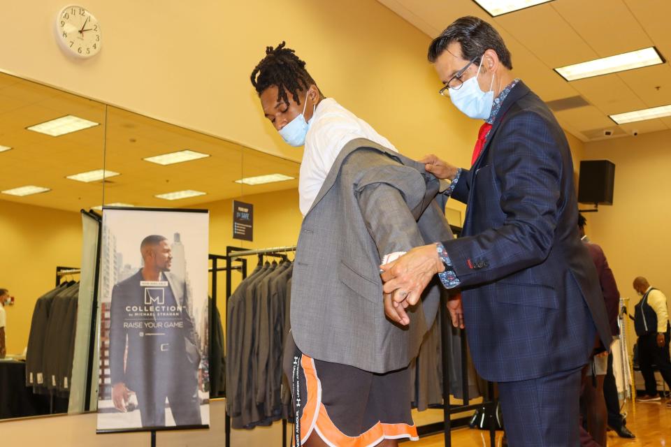 A Men's Wearhouse tailor (right) fits a Jackson State player for his new suit.