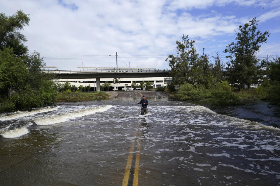 A television reporter stands in a flooded road after the passing of Tropical Storm Hilary, Monday, Aug. 21, 2023, in San Diego. (AP Photo/Gregory Bull)