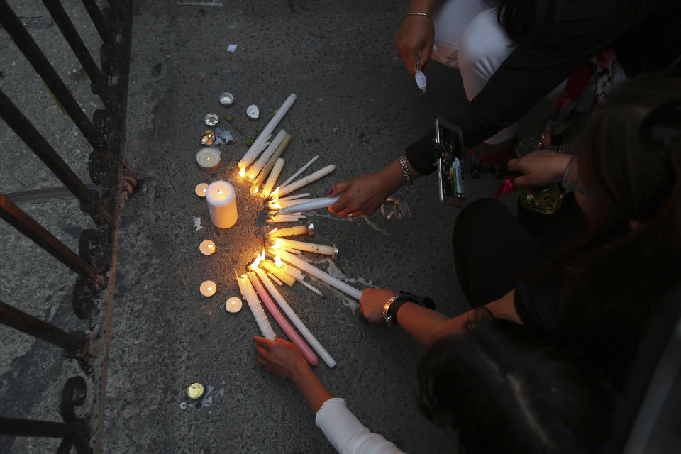 Women lights candles in memory of victims outside the presidential palace in Nicosia, Cyprus, Friday, April 26, 2019. Up to 1,000 people turned out in front of Cyprus' presidential palace to remember the five foreign women and 2 girls that a military officer has confessed to killing in what police are again calling "an unprecedented crime." (AP Photo/Petros Karadjias)