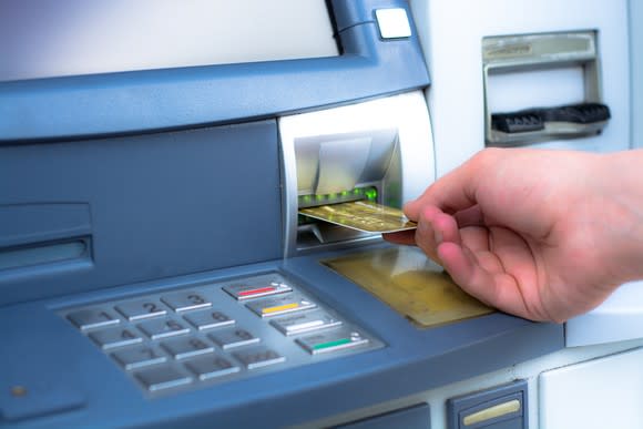 Hand inserting card into an ATM.